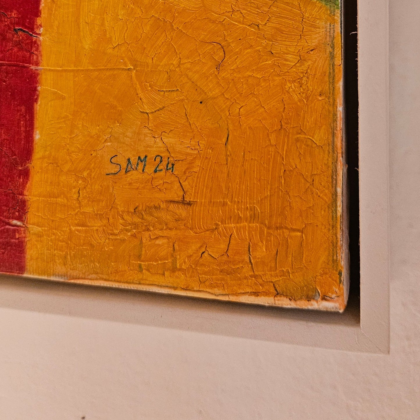 Corner of white framed abstract painting with artist signature "sam 24" on the corner