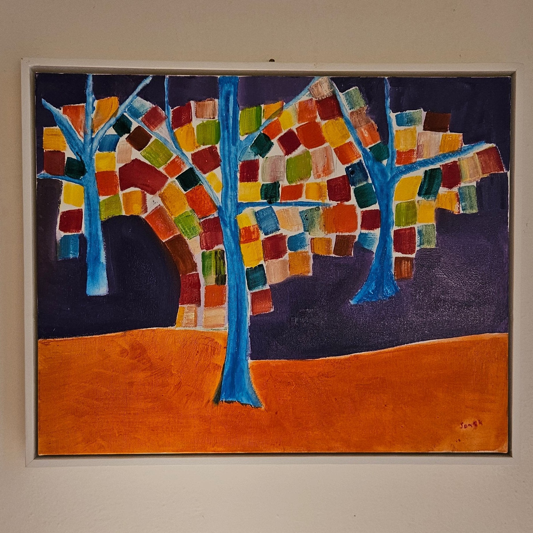 Angled photo of an abstract tree oil painting with 3 trees painted blue with colored square leaves and a purple and orange background. Painted by artist Edoardo Samasta Latour